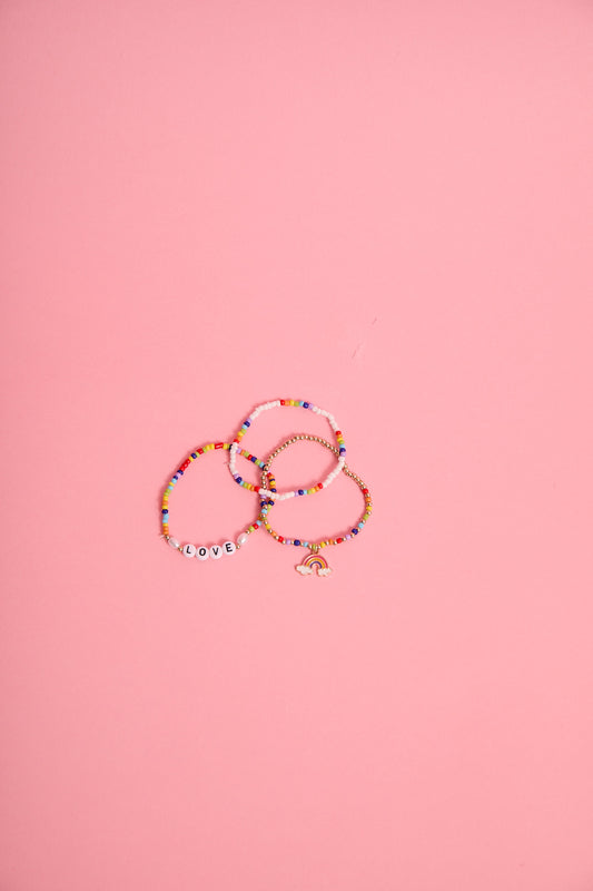 a group of beaded bracelets on a pink background